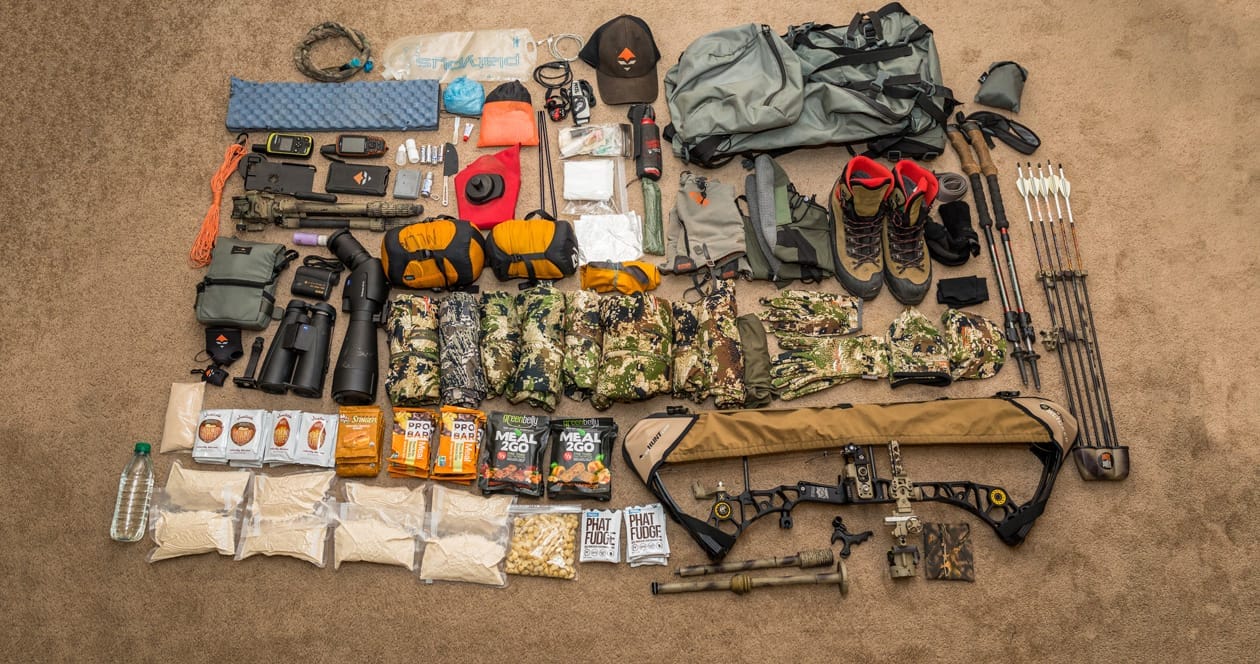 Backcountry hunter with gear hiking in mountain terrain