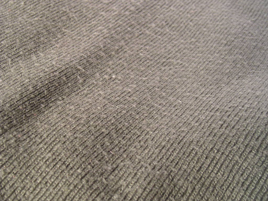 Close-up of fabric pilling on bed sheets showing rough texture and fiber balls