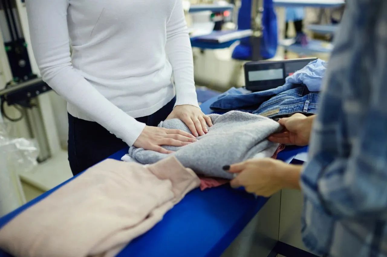 Close-up of fast fashion fabric quality inspection process showing textile composition and durability check