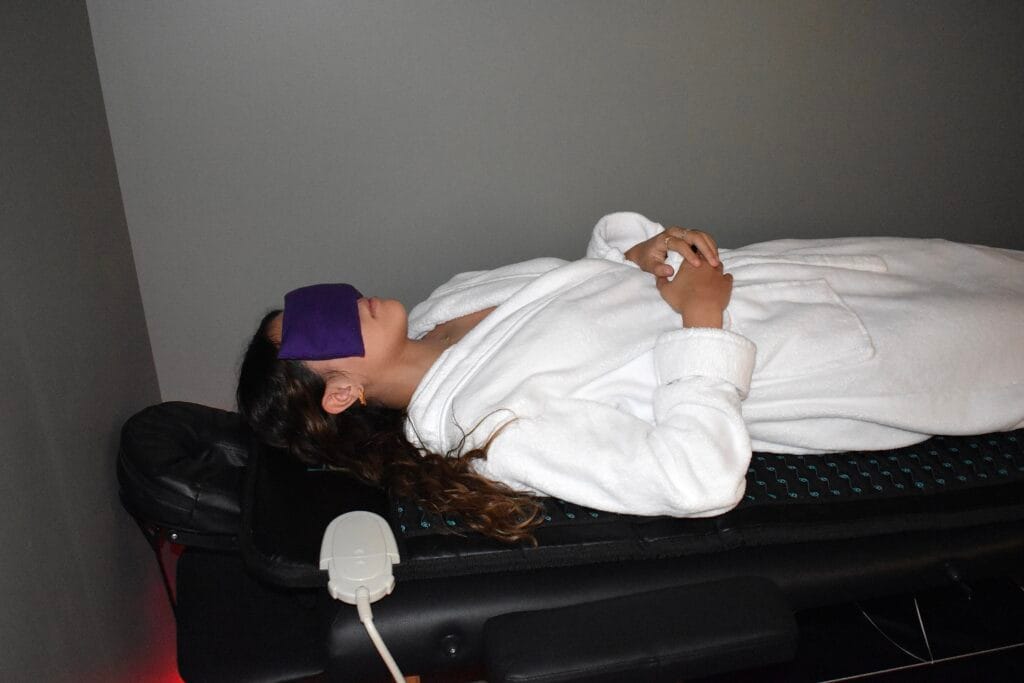 Infrared PEMF wellness mat session showing user relaxing with red light and heat therapy active