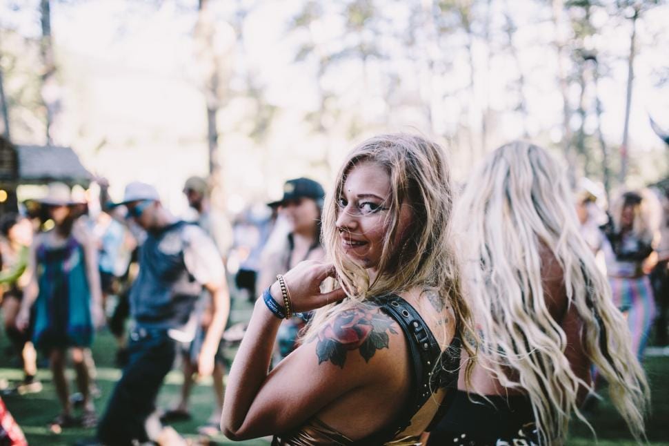 Smiling woman enjoying a music festival wearing trendy festival apparel and accessories