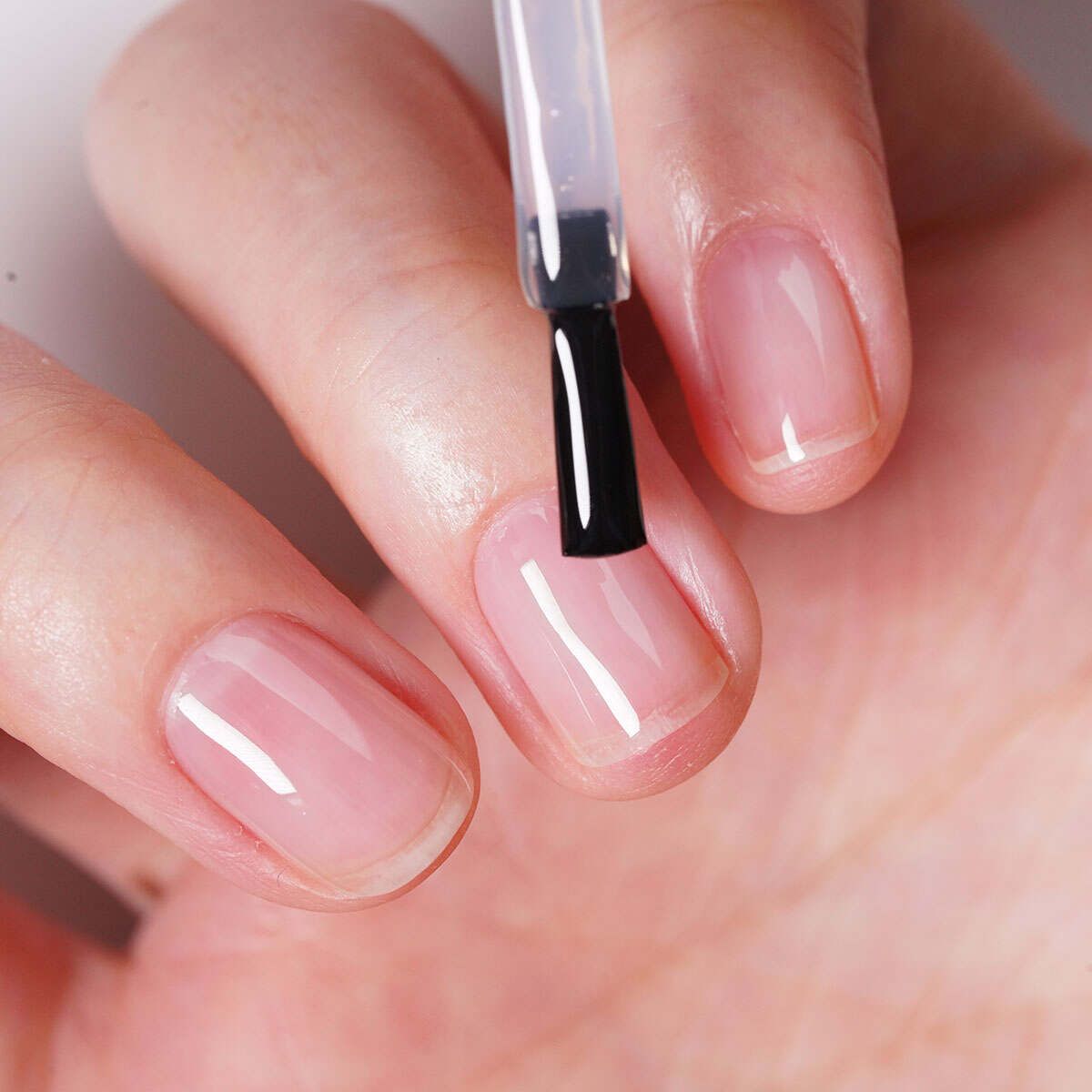 Glossy nail polish top coat application showing high-shine finish on natural manicure