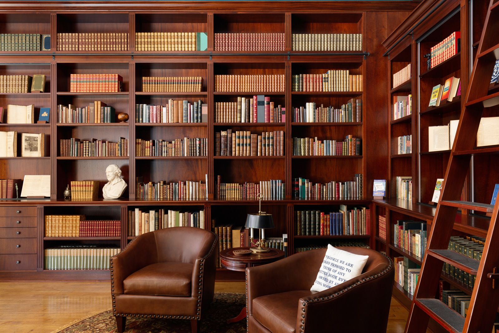 Rare book collector browsing hardcover volumes on library shelves for academic research