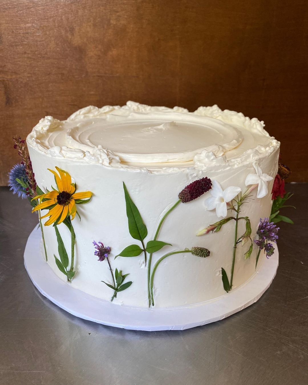 Butter Baked Goods signature layered birthday cake with pastel frosting rosettes on cake stand