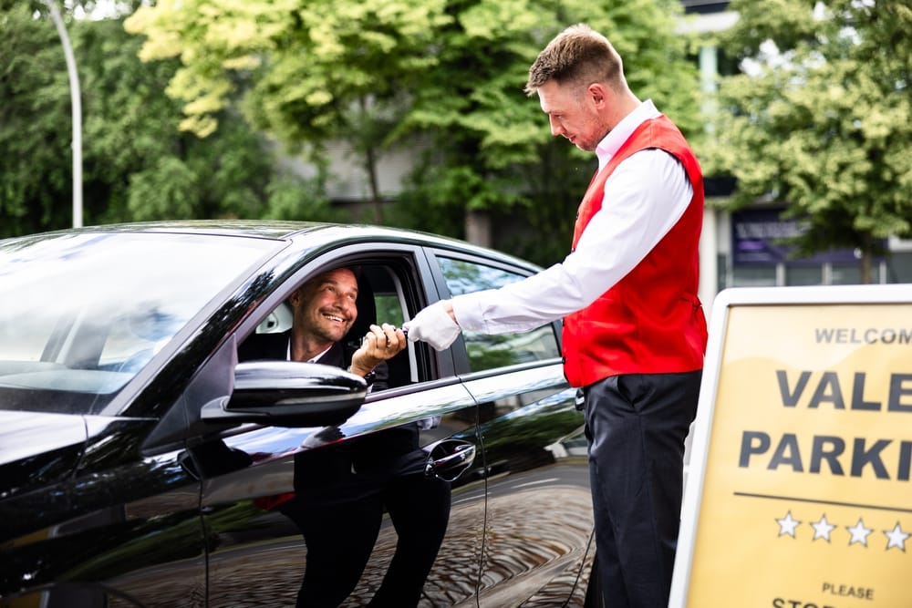 Meet and greet valet parking service handing car keys to attendant at airport terminal drop-off
